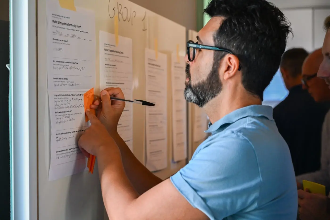Un founder aggiunge un post-it al canvas di posizionamento del suo gruppo