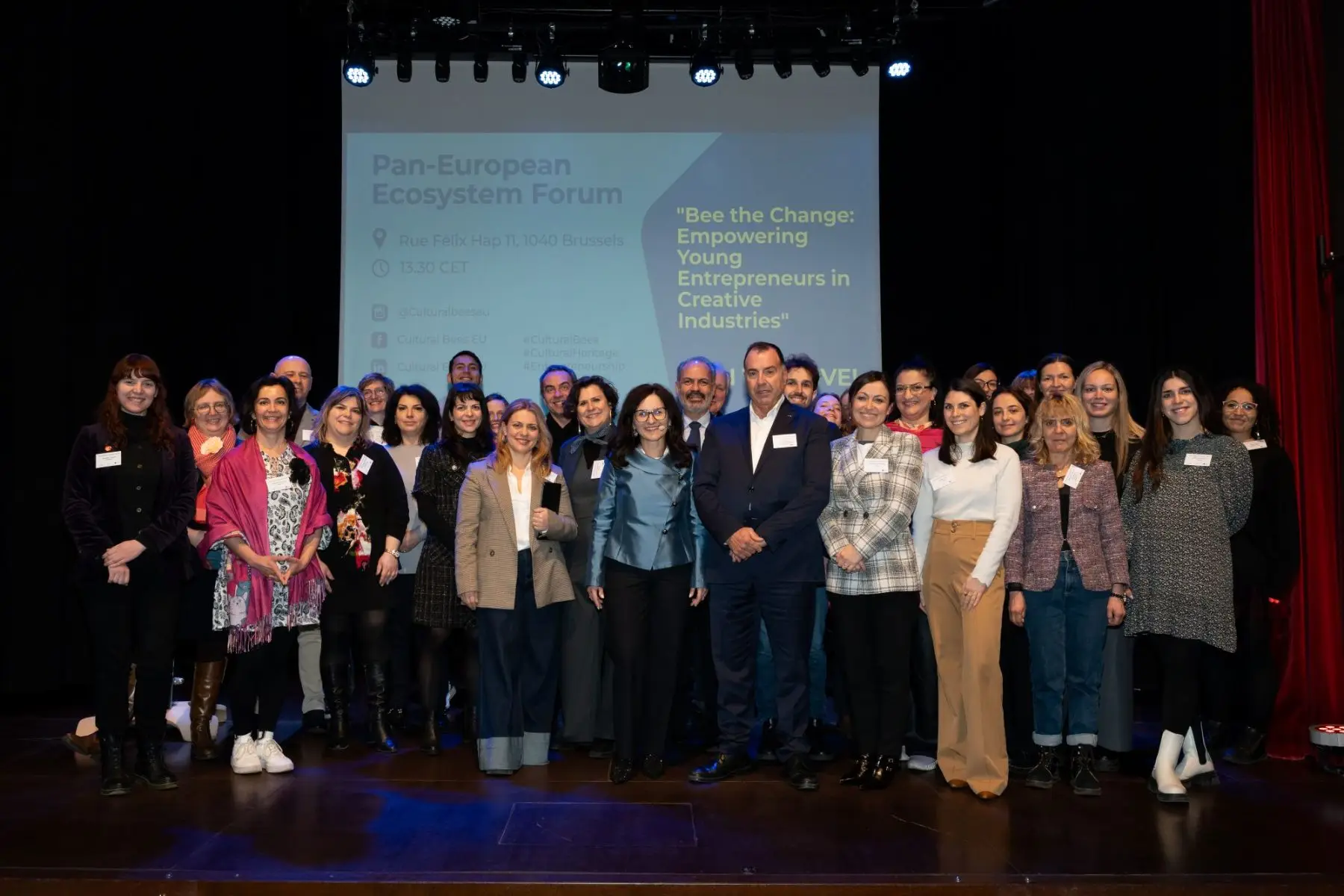 Foto di gruppo sul palco del Pan-European Ecosystem Forum a Bruxelles, davanti allo schermo con il titolo del forum