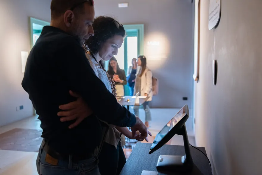 Visitatori davanti a una postazione interattiva della mostra