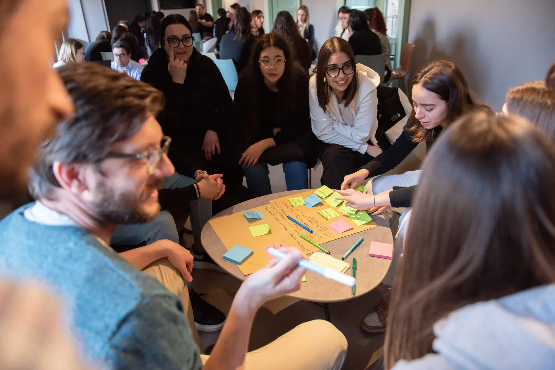 A facilitator works with a group sorting sticky notes on a poster