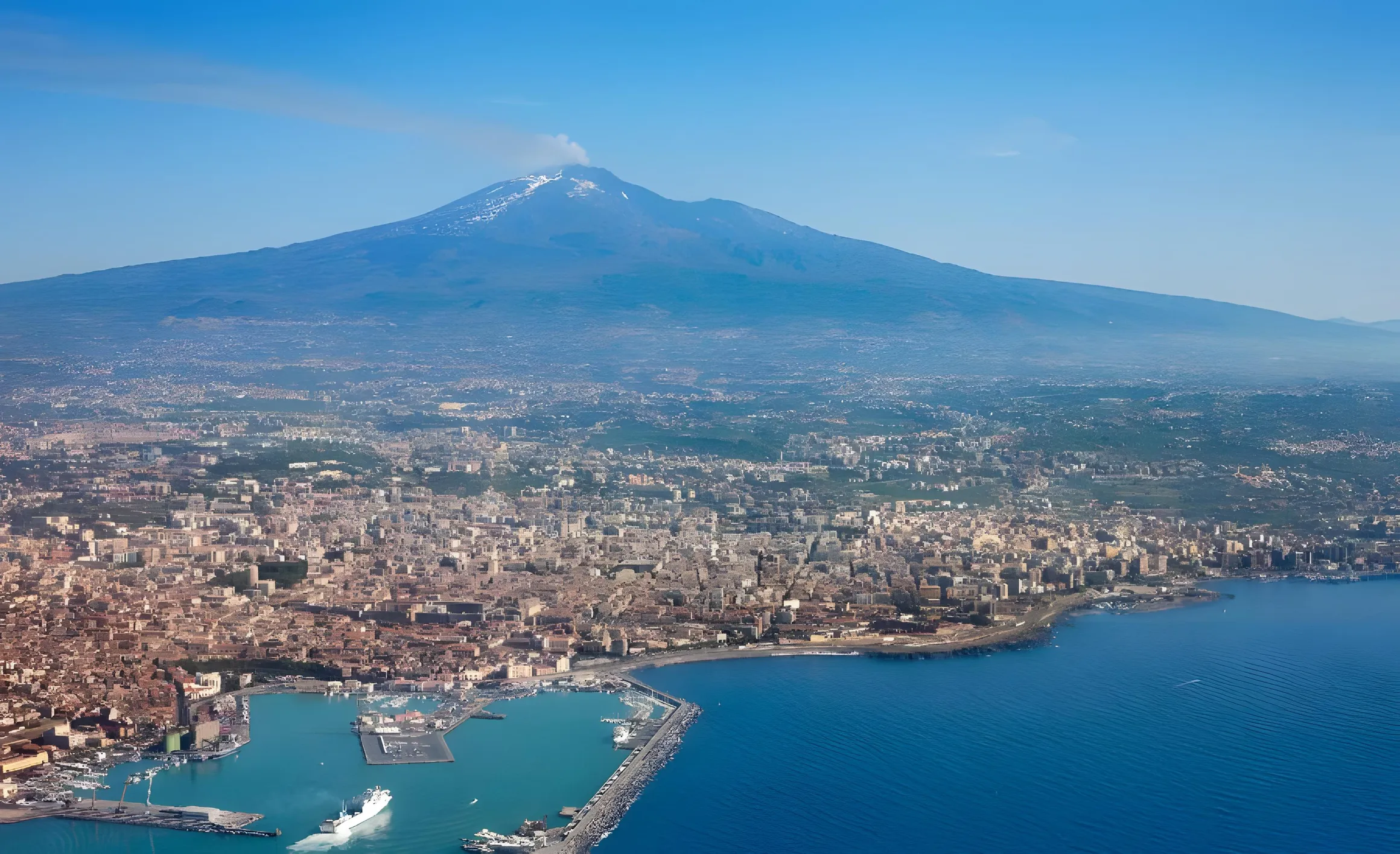 Catania vista dall'alto, con il porto, il mare e l'Etna sullo sfondo