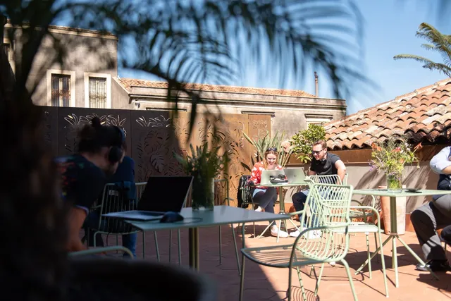 People working on the sunny terrace of the Isola Catania coworking