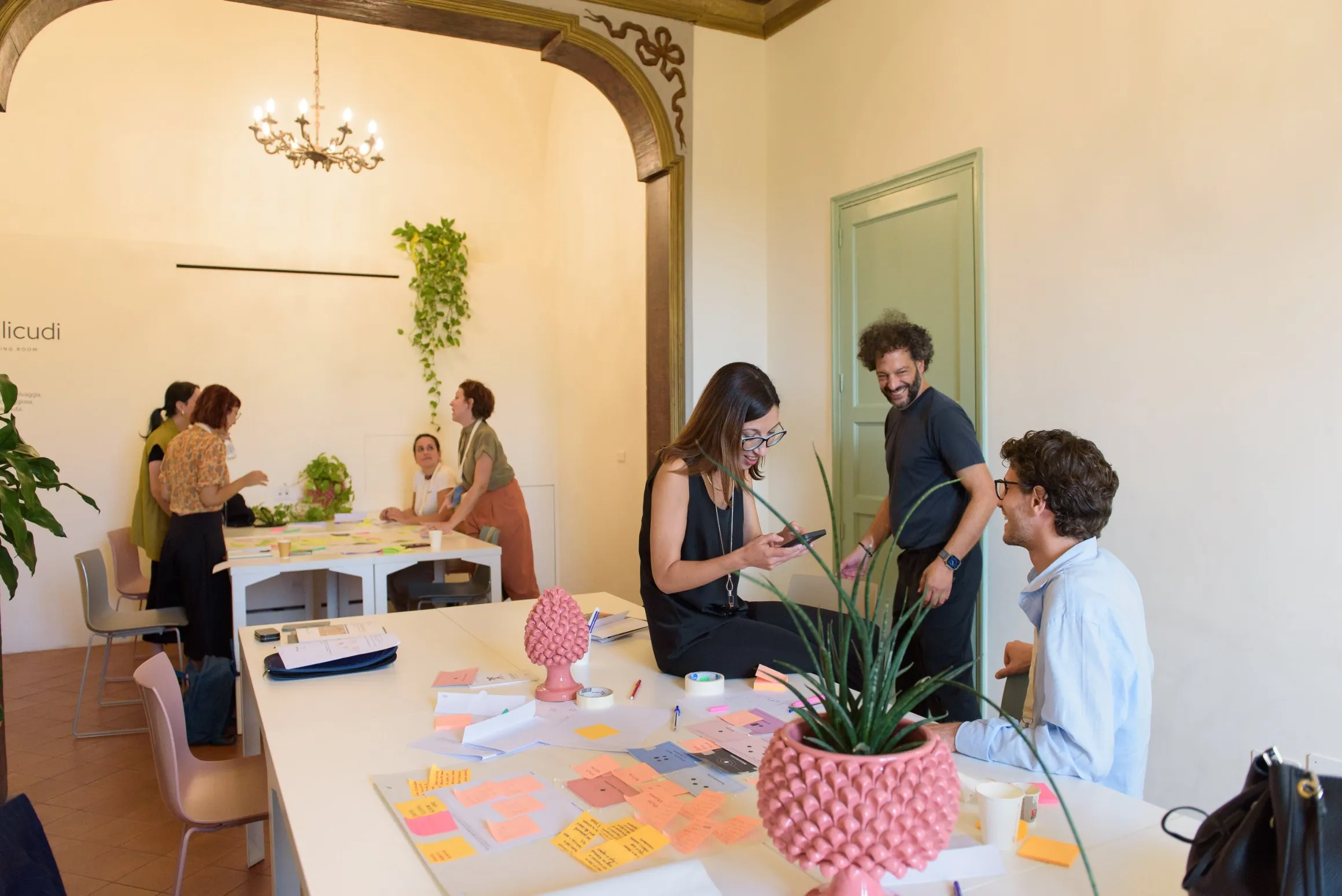 A co-design workshop at Isola Catania, with participants working around tables covered in sticky notes