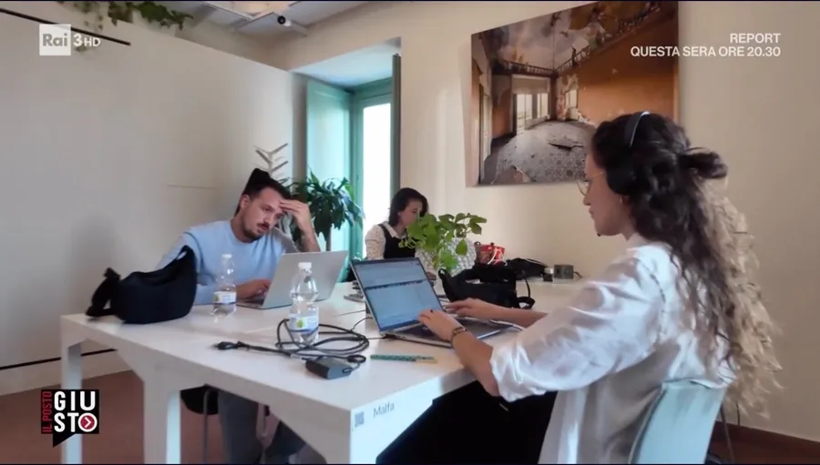 Fermo immagine del servizio di Rai 3: tre persone al lavoro nel coworking di Isola, sotto una fotografia di Palazzo Biscari
