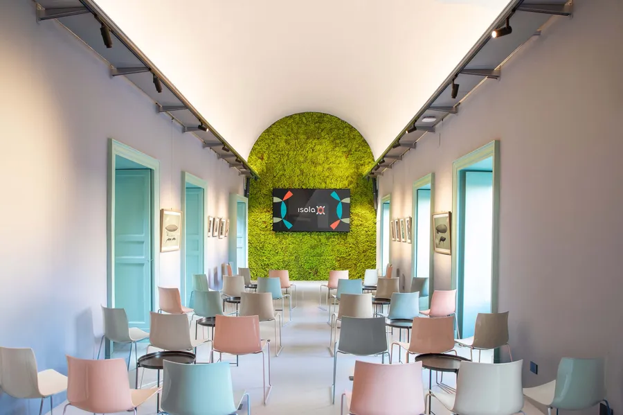 La sala Sicilia di Isola a Catania, allestita a platea con tavolini, verso la parete verde
