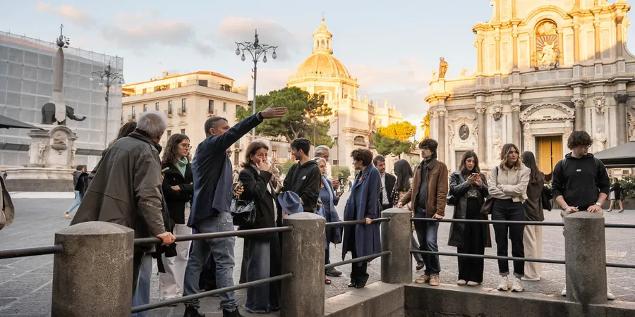 A group of people of different generations in Piazza Duomo in Catania, in front of Sant’Agata Cathedral and the Liotro elephant